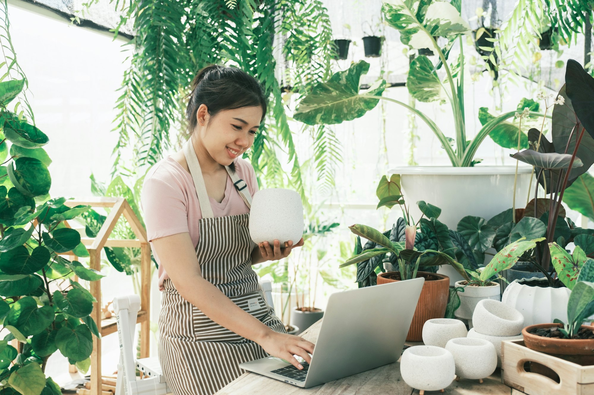 Young woman plant shop owner is checking customer order from website